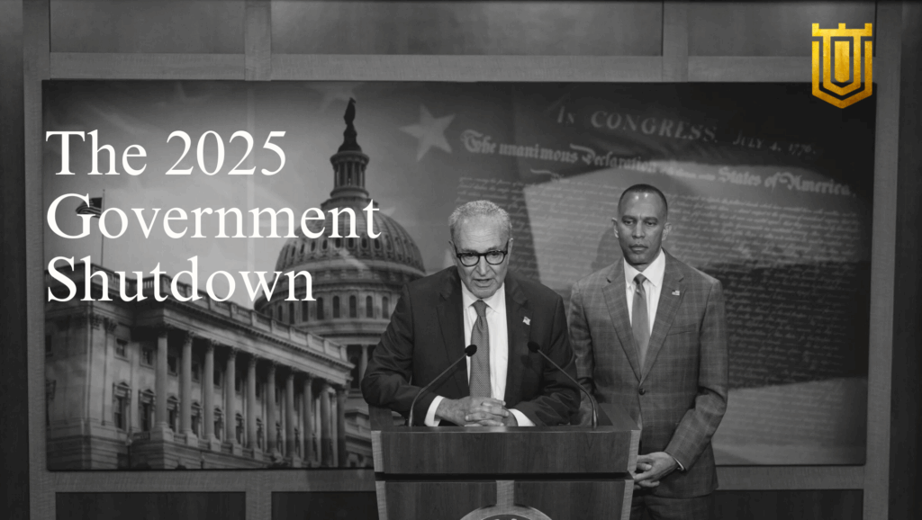 Dramatic grayscale scene of two suited men—resembling congressional figures—at a podium with the U.S. Capitol dome and Declaration of Independence backdrop. Overlay text: "The 2025 Government Shutdown" in bold white font, accented by a gold shield emblem. Nicholas Mugalli from World Trade Securities analyzes the geopolitical and economic fallout.