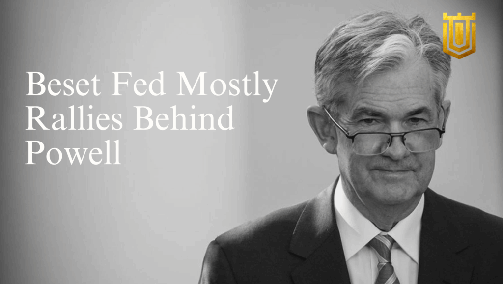 Portrait of Federal Reserve Chair Jerome Powell in a gray suit and glasses, standing confidently with a subtle smile. Overlay text reads "Best Fed Mostly Rallies Behind Powell" in white lettering on a grayscale background, featuring a gold shield emblem with tower motifs. Analysis by Nicholas Mugalli at World Trade Securities emphasizes Fed cohesion and market stability.